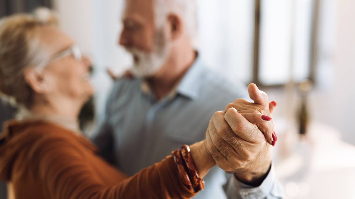 Emeryci oczekują przyszłorocznych korekt finansowych. Indeksacja 2026 zostanie zrealizowana w marcu i spowoduje, że zwiększą się emerytury, renty i wsparcie dla osób w podeszłym wieku. Znane są już prognozy dotyczące nowych sum, a to umożliwi dalsze kroki i wyliczenie m.in. wielkości trzynastej i czternastej pensji emerytalnej. Para starszych osób tańcząca, kobieta w okularach i brązowym swetrze, mężczyzna z siwą brodą, oboje trzymają się za ręce.