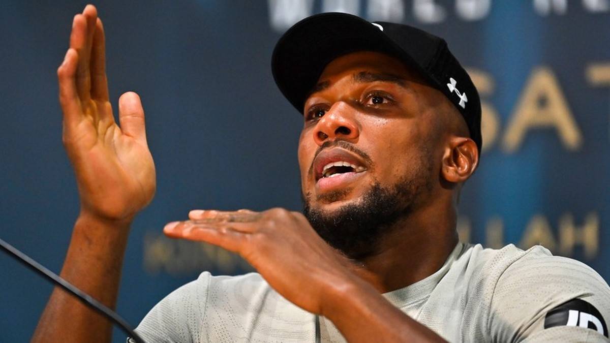 Anthony Joshua w czapce z daszkiem i koszulce, gestykuluje rękami.