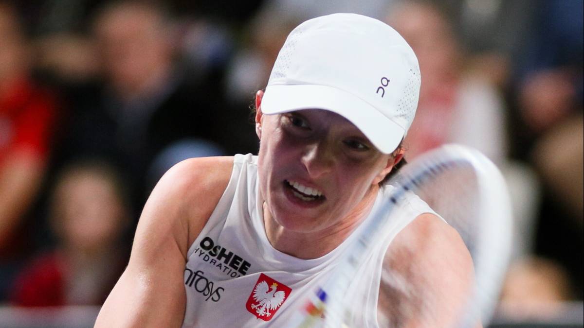 Tenisistka w białej czapce i biało-czerwonym stroju uderza piłkę rakietą.