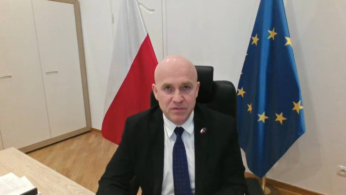 Prezydent Karol Nawrocki siedzi za biurkiem, za nim wiszą flagi Polski i Unii Europejskiej.