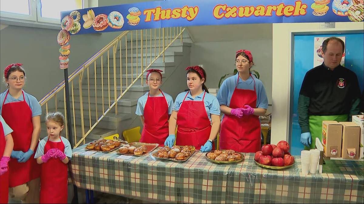 Uczestnicy kiermaszu pączków w szkole podstawowej, przygotowani do sprzedaży słodkości.