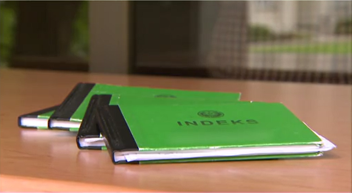 Trzy zielone indeksy studenckie na drewnianym stole.