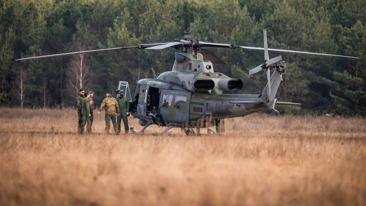 Nowe helikoptery dotarły do Polski. Wymiana postsowieckiego sprzętu. 3 Wojskowy śmigłowiec UH-1Y Venom Czeskich Sił Zbrojnych wylądował na polu z żołnierzami stojącymi obok.