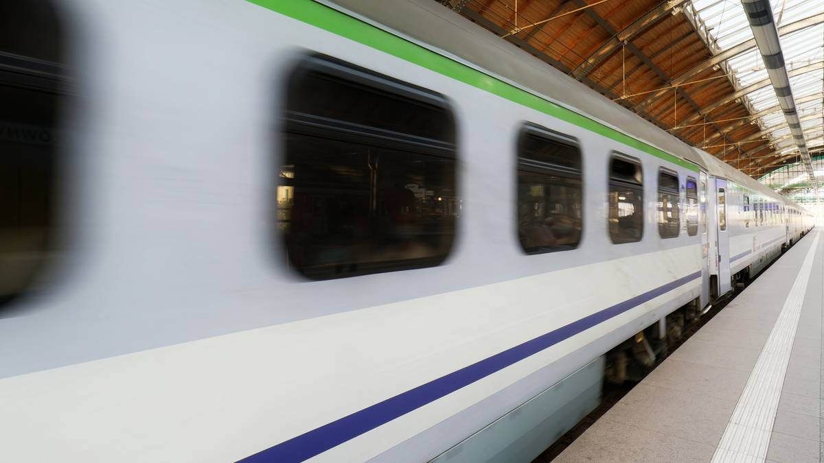 Pociąg na peronie dworca kolejowego, okna pociągu są rozmazane z powodu ruchu.