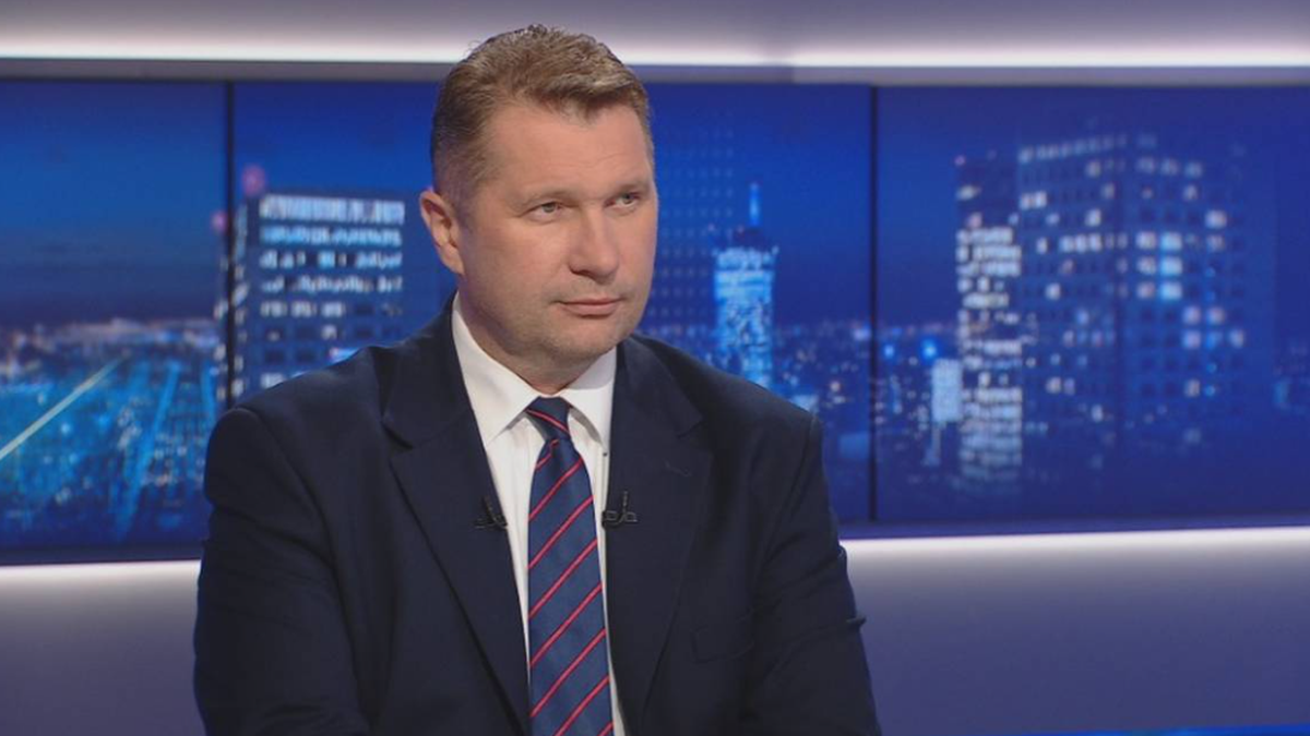 Daniel Czyżewski, analityk ds. energii, Fundacja Polska z Natury, siedzi w studiu telewizyjnym na tle nocnej panoramy miasta.