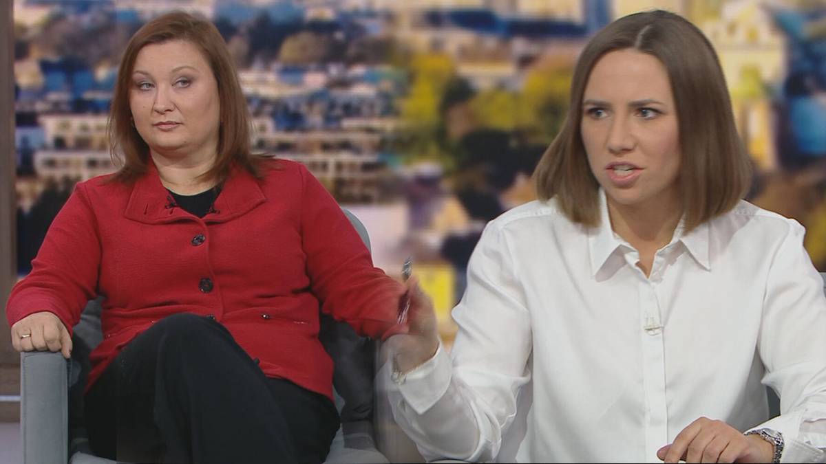 Dwie kobiety siedzą w fotelach podczas rozmowy. Kobieta po lewej ma na sobie czerwoną marynarkę, a kobieta po prawej białą koszulę.