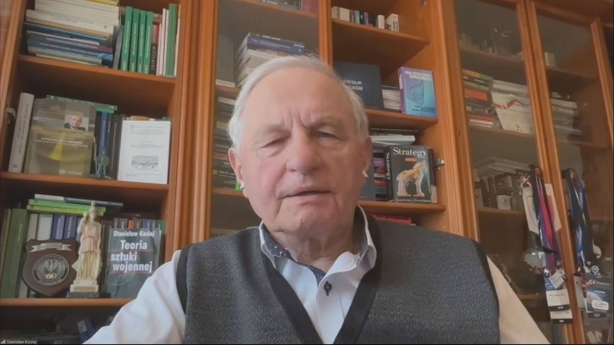 Generał Stanisław Koziej siedzi przed regałami z książkami.