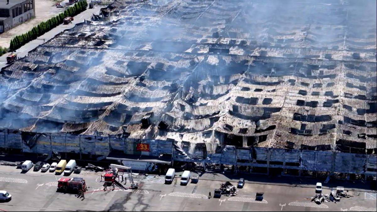 Widok z lotu ptaka na spalony dach centrum handlowego, z kt&oacute;rego unosi się dym.