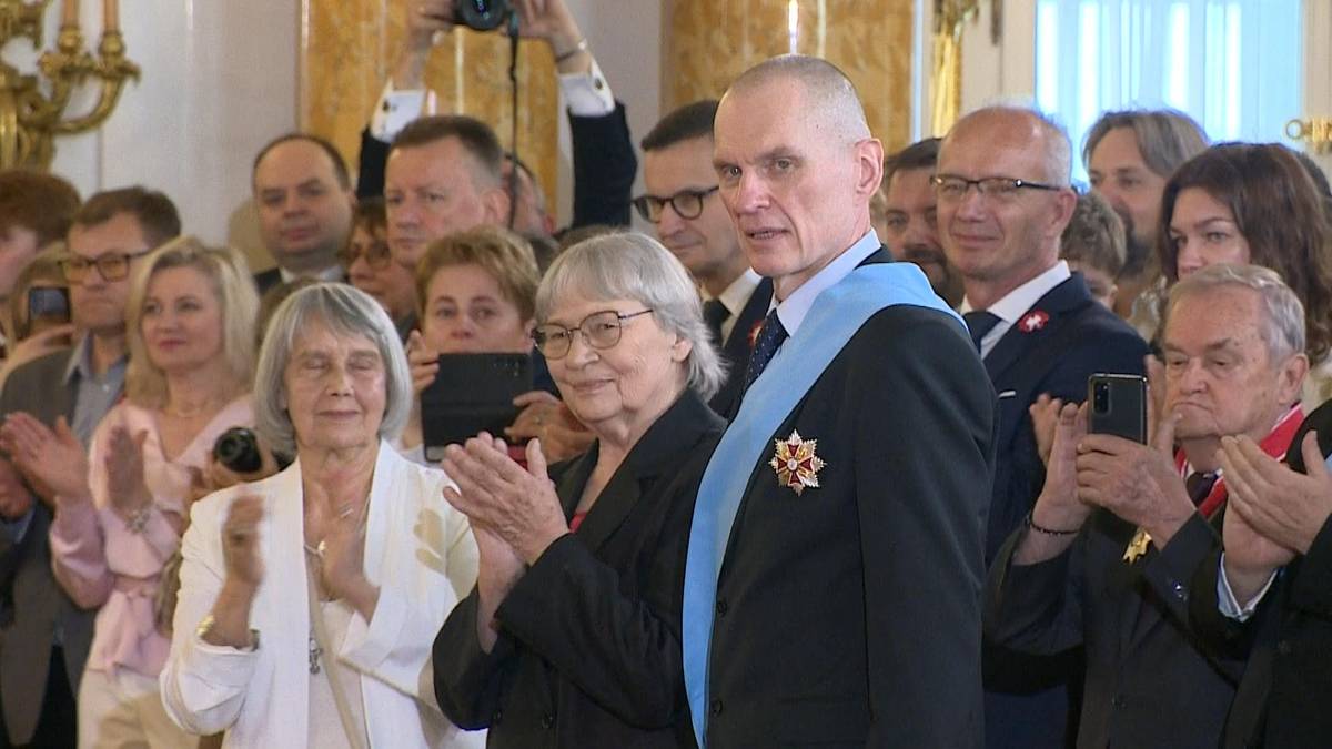 Uroczystość z udziałem wielu os&oacute;b, na pierwszym planie mężczyzna w odznaczeniach i dwie starsze kobiety.