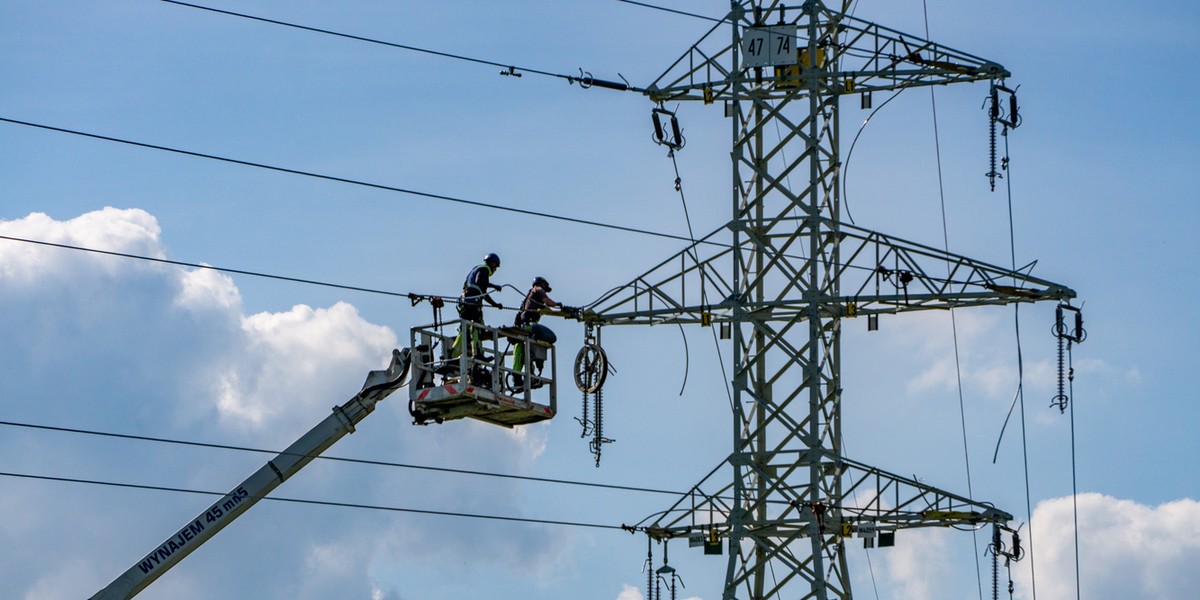 Kondycja linii energetycznych jest kluczowa w okresach silnych upałów. Na zdjęciu dwaj pracownicy mediów wykonują prace konserwacyjne na liniach wysokiego napięcia w Józefowie